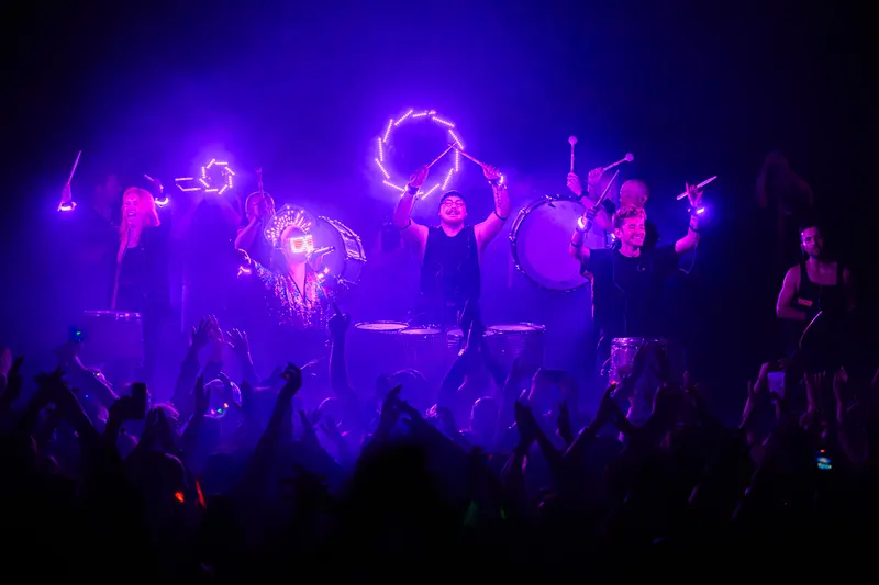 Flash Bang Brass performs under purple lights as the audience raises its hands.
